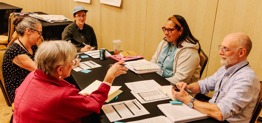 A group of five people wortk around a table