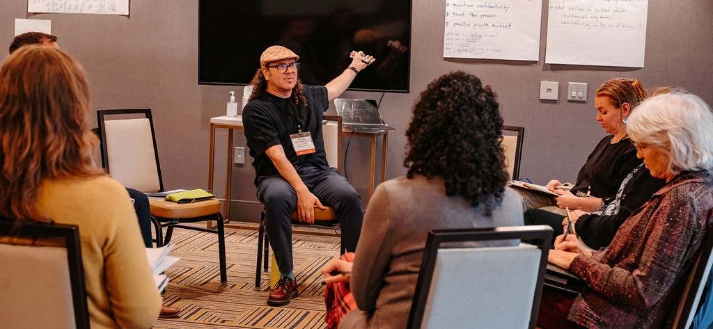 Facilitator pointing to a screen in a rool with participants